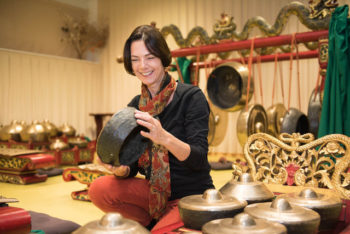 pratique artistique : Sylvie Chantriaux souriante et assise au centre de son gamelan javanais Kyai Kumandang