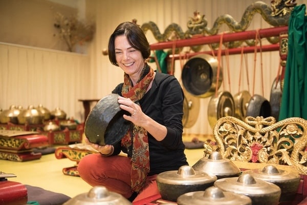 Sylvie Chantriaux souriante et assie au centre de son gamelan javanais Kyai Kumandang