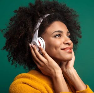 Festival Entendez-Voir ! Une femme métissée et souriante écoute un podcast au casque