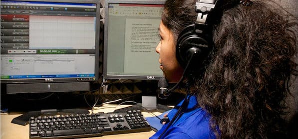 une femme avec un casque d'écoute installe sur l'ordinateur une interview à distance